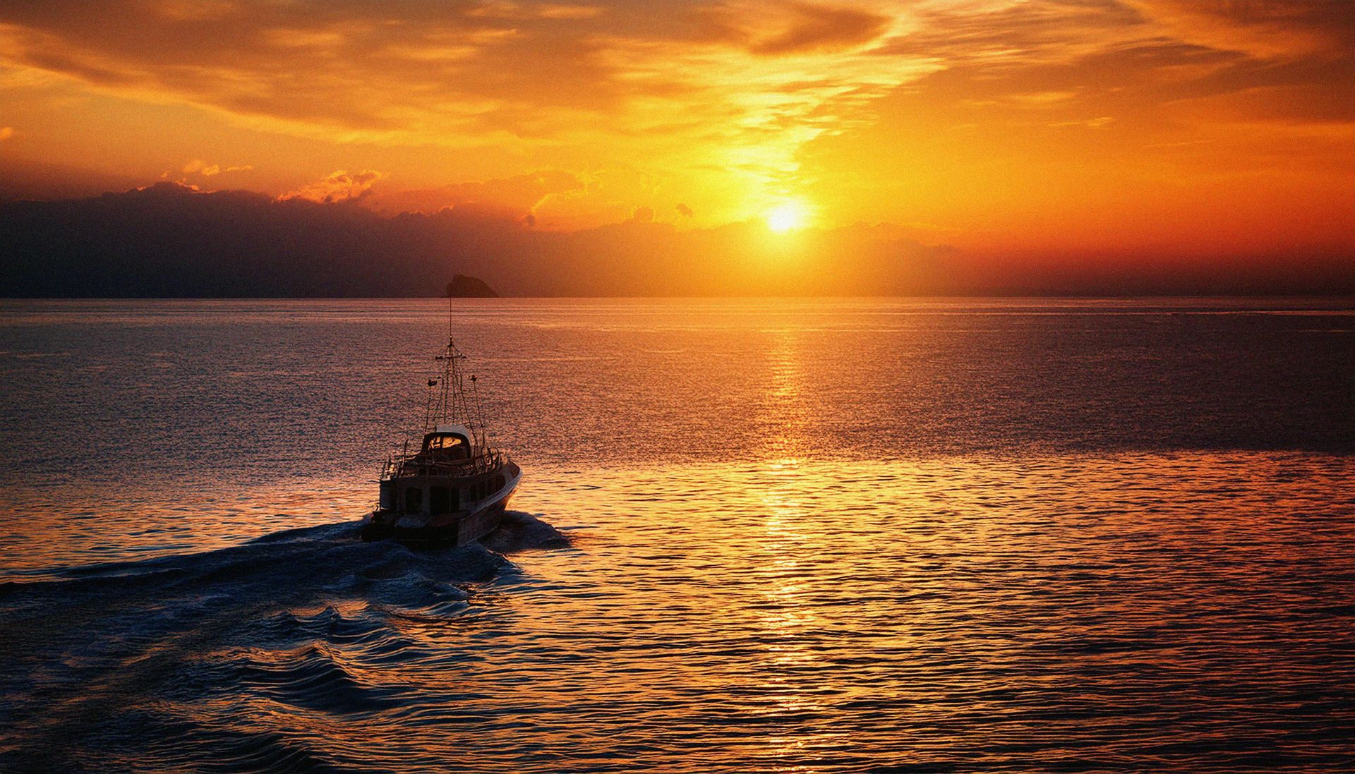 A boat traveling across a body of water at sunset